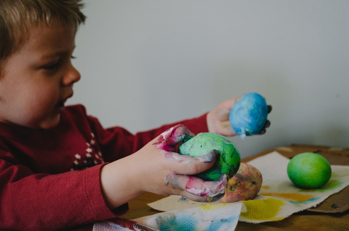 child-painting-easter-eggs-blue-green-min