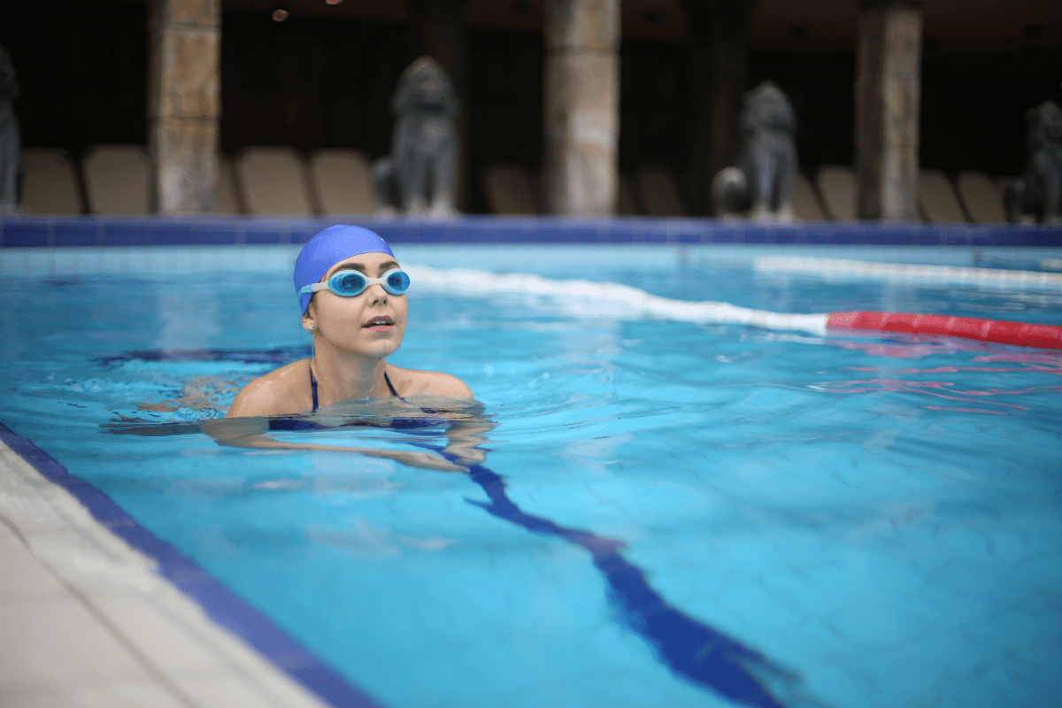 girl swimming in pool in swim cap goggles-min