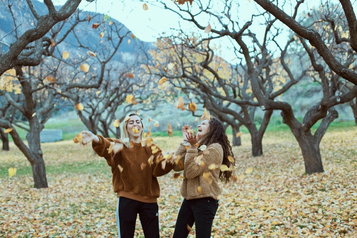 girls-in-sweaters-throwing-leaves