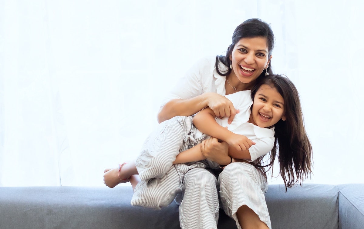 mother-and-young-daughter-smiling-holding-each-other-min