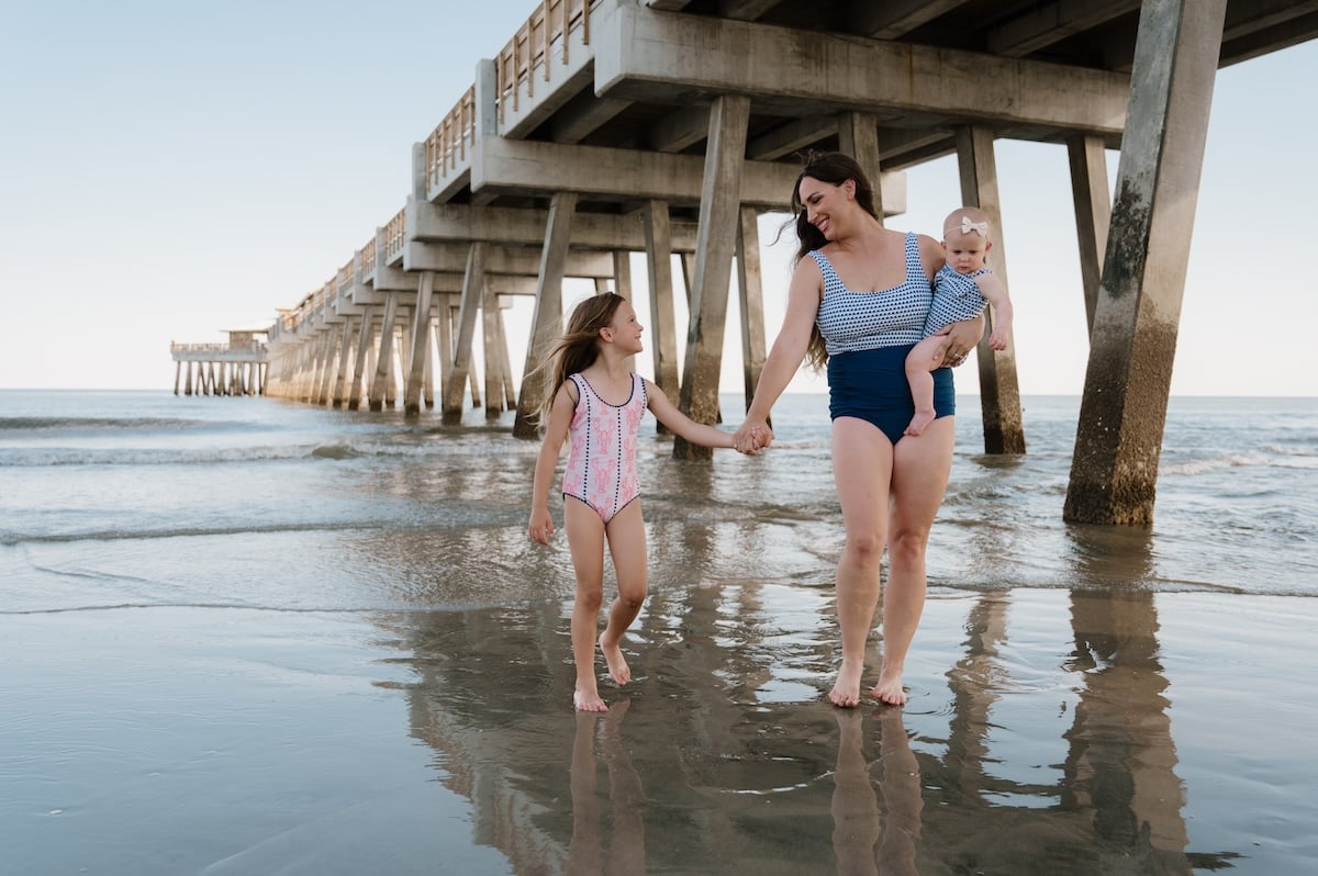 mother-daughter-walking-under-pier-holding-hands