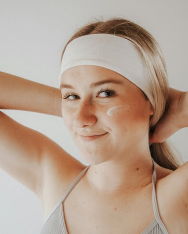 woman wearing headband and dabs of facial lotion on cheeks Large