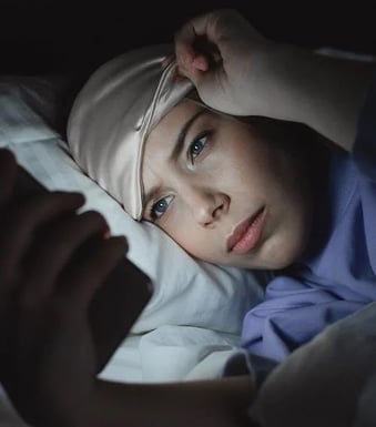 woman-checking-phone-at-night-in-bed-min