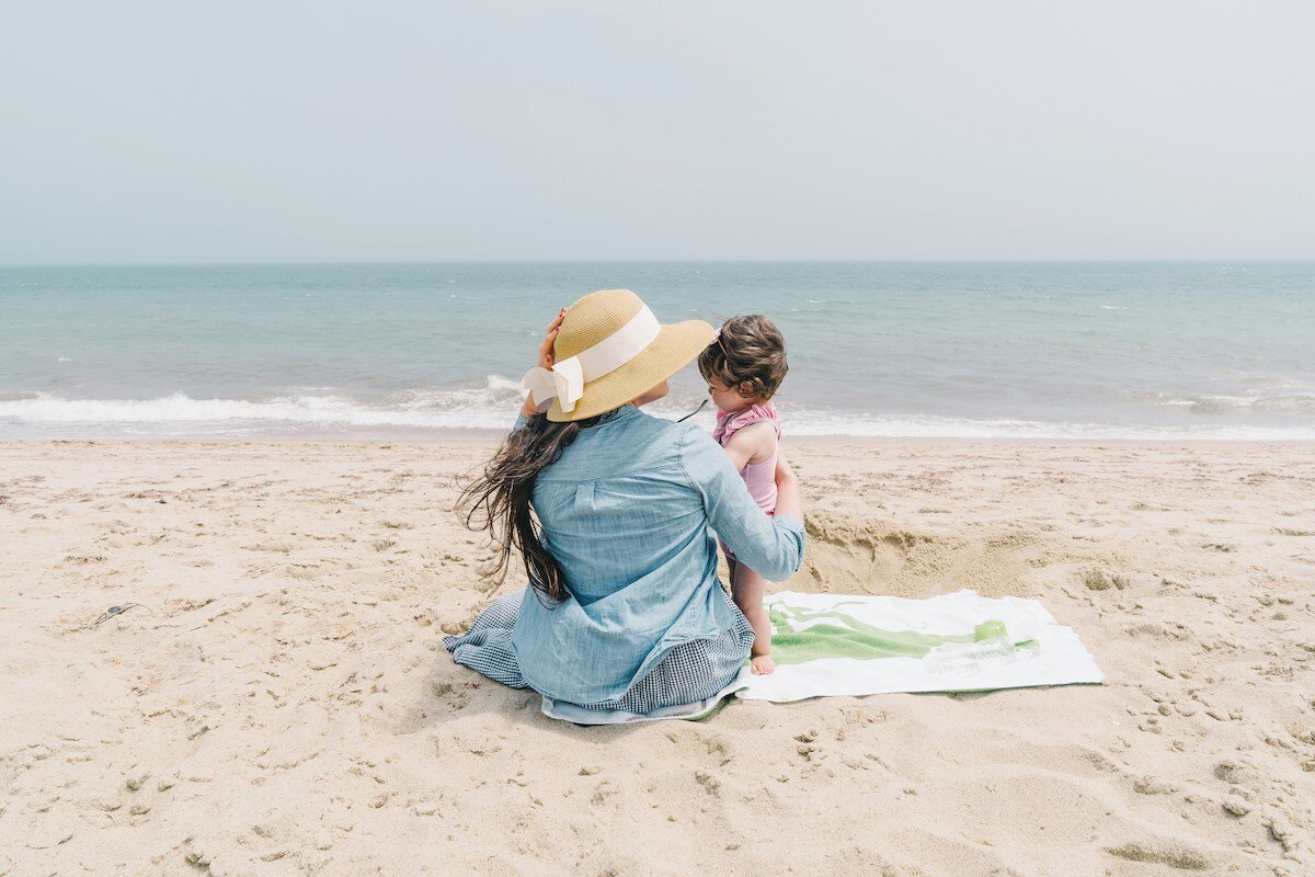 woman-in-wide-brim-hat-toddler-sitting-on-beach