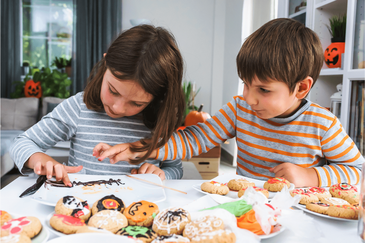 young-girl-and-boy-decorating-homemade-cookies-for-halloween-min